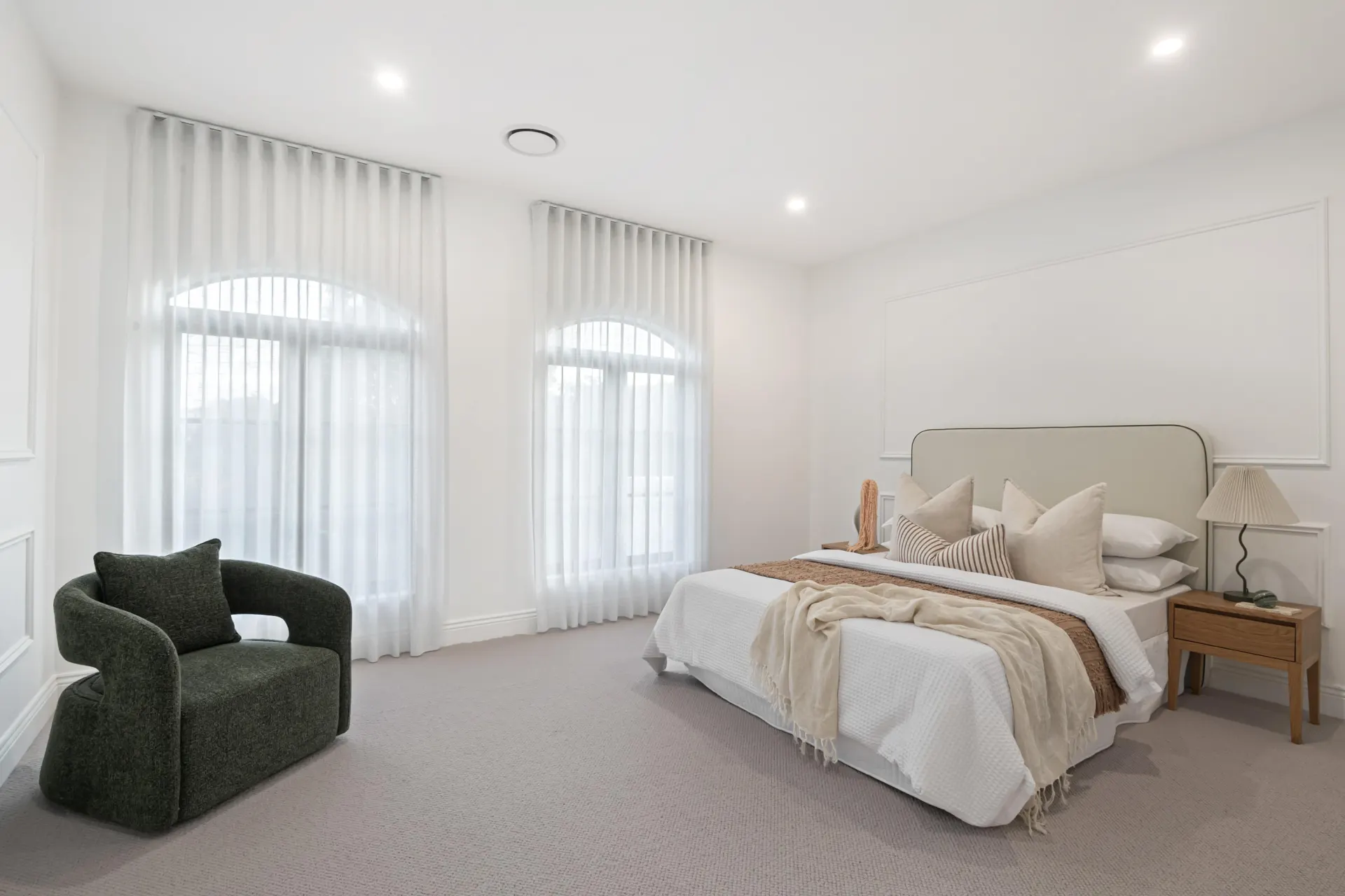 Bedroom with soft wool carpet and arched windows.
